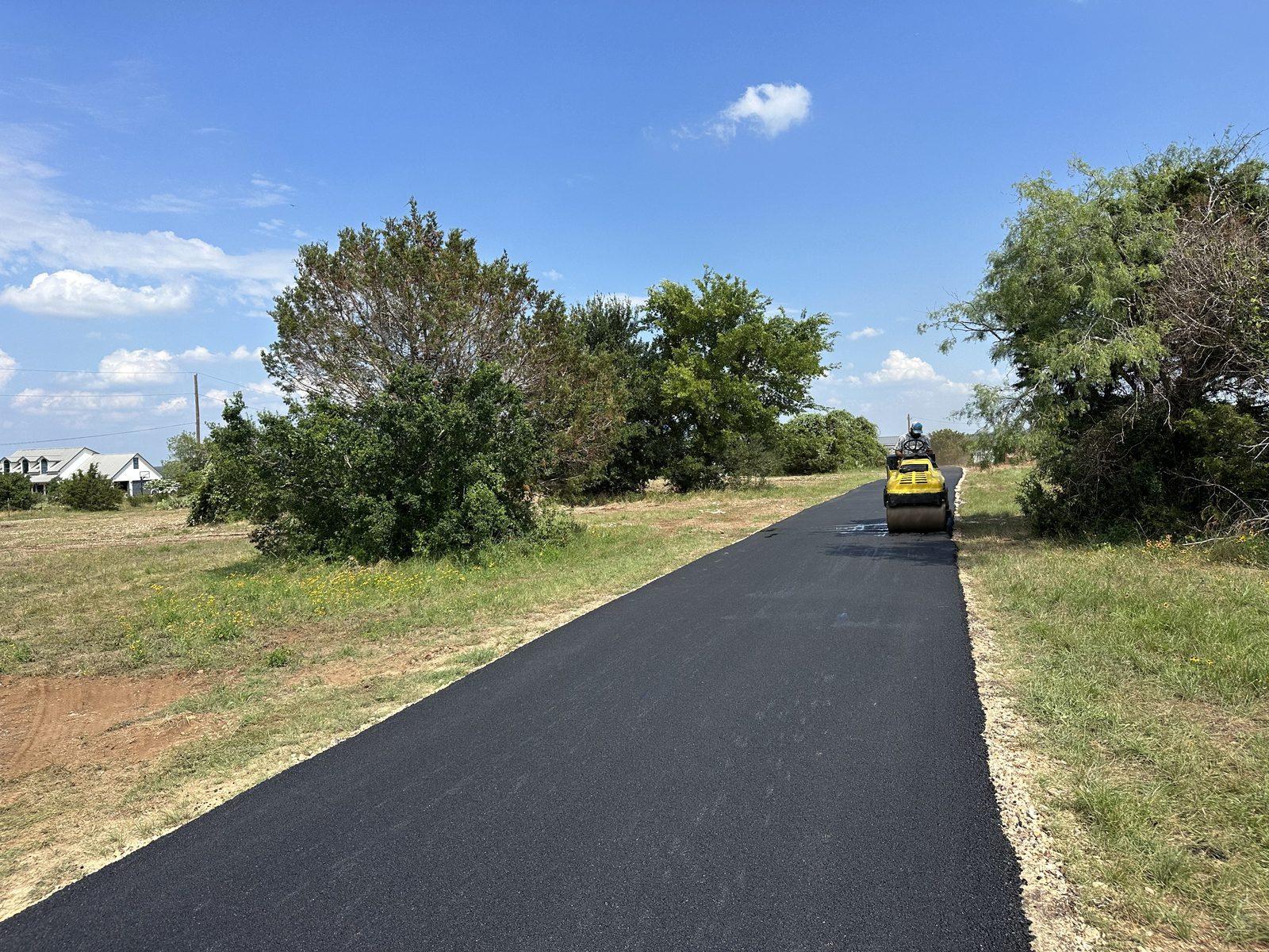 A Lonestar Construction Industries crew compacting a freshly paved asphalt road in the San Antonio area