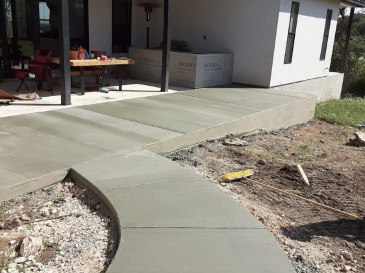 A curved concrete walkway freshly poured and finished at a modern San Antonio area home by Lonestar Construction Industries